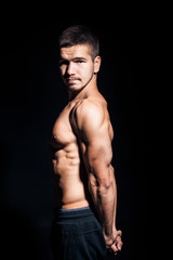 Fototapeta premium young handsome man with perfect torso on black background;