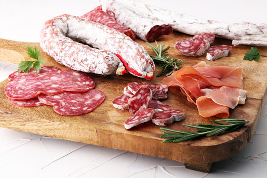 Wooden cutting board with prosciutto, salami, sausages  and  rosemary