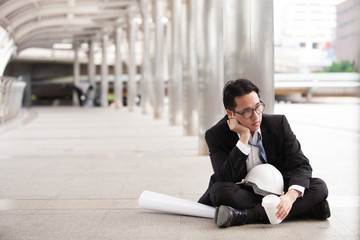 Stressful businessman or engineer sitting outdoor thoughtful thinking with hopeless