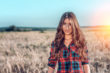 Beautiful happy girl in the field, sunny afternoon, shorts shirt. The concept of enjoying nature. Rest on the air. Walking through the meadows in wheat in the summer. Beautiful hair Happy smiling