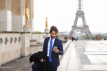 Hispanic businessman calling partner with phone near Eiffel Towe