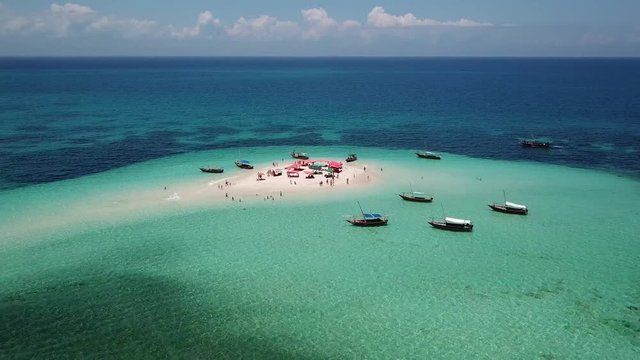 Aerial view of beautiful sand tropical island with white sand beach and tourists. White sand island. Seascape: ocean and beautiful beach paradise. Zanzibar, Tanzania. 4K video. Travel concept