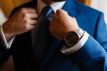 The man in the blue suit straightens his jacket. Businessman in classic suit with expensive...