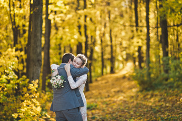 Fototapeta premium Embrace of the newlyweds on background of Sunny autumn forest 24.