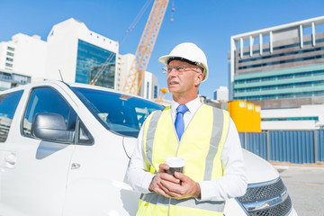 Engineer builder on construction site at sunny day with coffee in hand