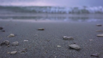 Sea tidal wave at night splashing pebbles at sandy beach