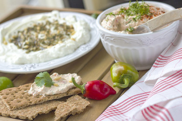 Middle Eastern dish - dense homemade labneh yoghurt with zatar in white dishes, on a wooden aged surface. Daylight.