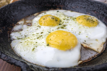 appetizing fried eggs in an old frying pan
