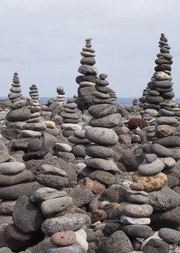 large towers of stacked pebbles on a beach with blue sky