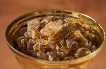 Brown cane sugar is lumpy inside the bowl of the golden cup. The concept is the sweet taste of victory.