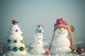 Snowmen with smiley faces in hats on winter day