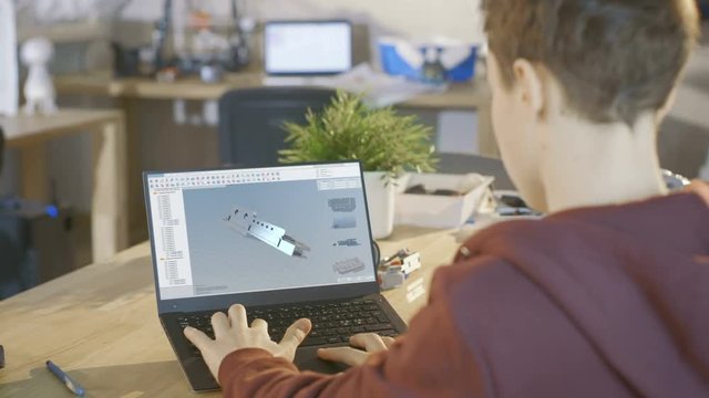 Boy Uses Laptop Computer to Make 3D Designed Component in CAD Program for His Scientific Robotics Class.