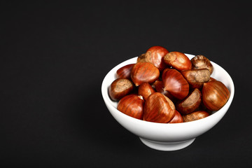 Ripe organic chestnuts heaped in a white bowl 