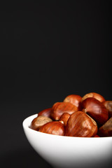 Ripe organic chestnuts heaped in a white bowl