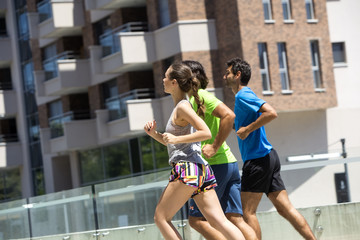 Obraz premium Two young men and woman running in urban enviroment