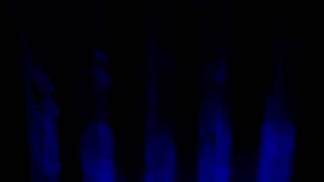 Blue spotlight and smoke on black background. Abstract dark background with bright blue stage spotlights. Lights and smoke. Row of blue lights from a stage.