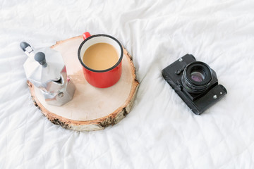 Coffee mug with coffee maker on tray with vintage camera on bed