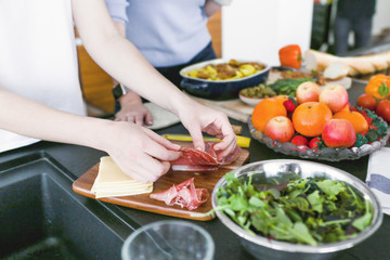Women preparing dinner at kitchen with jamon