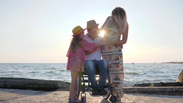 invalid in wheelchair with little daughter rubbing to mothers pregnant belly is a happy family