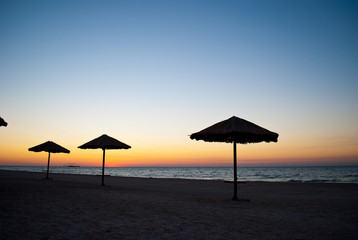 several a lot of big beach umbrellas made of straw and metal stand on the beach sand beach blue sea blue sky summer morning evening calm