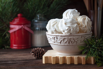 Homemade zephyr or marshmallows with pine-tree branches, cones, spices, Christmas atmosphere, wooden background