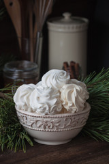 Homemade zephyr or marshmallows with pine-tree branches, cones, spices, Christmas atmosphere, wooden background