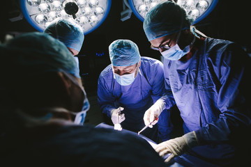 Team of professional surgeons performing surgery - obrazy, fototapety, plakaty