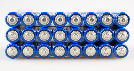 Lots of blue batteries, type AA, Packed in polyethylene film, on a white background, macro
