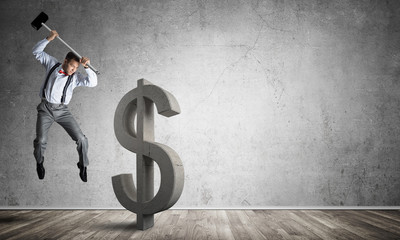 Determined banker man in empty concrete room breaking dollar figure