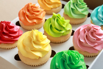 Tasty colorful cupcakes in cardboard box, closeup