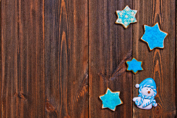 Christmas gingerbread cookies of blue star with Christmas-tree toys - snowman on brown wooden table. Copy space.