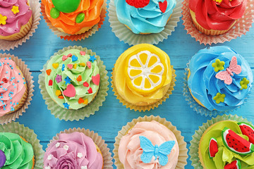 Beautiful cupcakes on color wooden background, top view