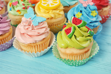 Beautiful cupcakes on color wooden background