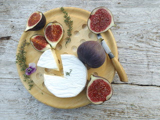 Cheeseboard. Brie cheese and figs on a round wooden board
