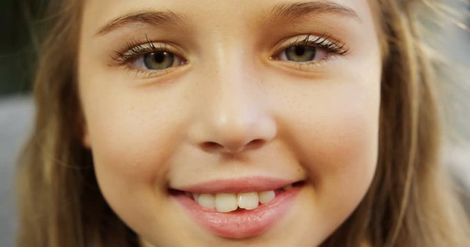 Close up of a little blonde cute girl face. Girl blinking her eyes and smiling. Inside. Portrait shot