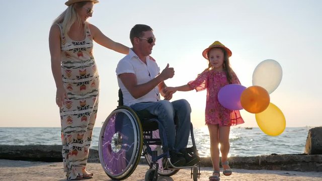 happy men with handicap woman and kid in backlit on the sea
