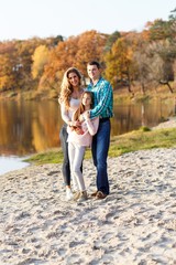 A happy family having fun in the park in autumn walking and hugging. Family, love, happiness concept. Family of three with mother father  and a little daughter