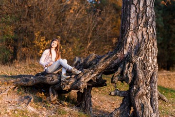 A girl having fun in the park in autumn sitting on a stump. Family, love, happiness concept. 