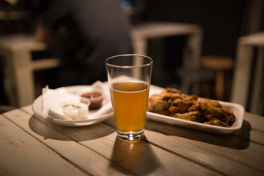 Beer, chicken wings and sauce on a table
