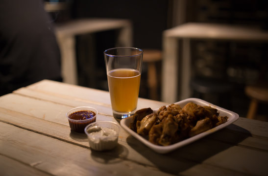 Beer, chicken wings and sauce on a table