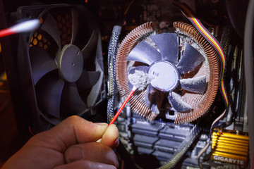 Male hand cleaning the dust from the computer fan with a cotton swab.