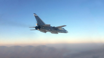 Fototapeta na wymiar Military jet bomber Su-24 Fencer flying above the clouds.