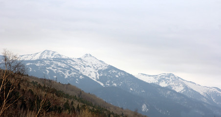 Fototapeta na wymiar Mountain ridges covered with snow and overcast sky.