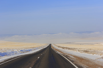Fototapeta na wymiar Winter road leaving into distance into the mountains