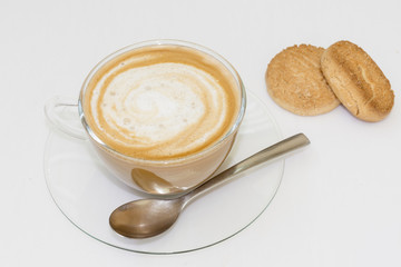 Un café con leche, en una taza de cristal transparente y dos pasteles