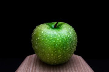 Fresh green apple on a wooden board with black background