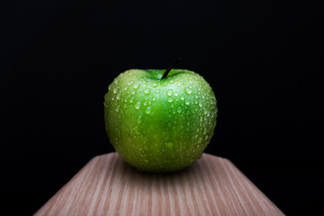 Fresh green apple on a wooden board with black background