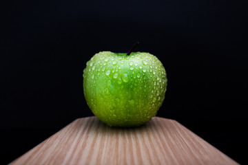 Fresh green apple on a wooden board with black background
