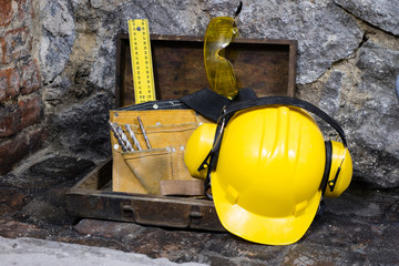 Construction tools for building a house on a stone wall. Hammer, helmet, and other necessary tools...