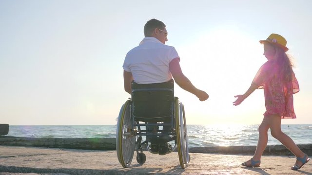 pregnant girl keeps arm disabled man in wheelchair holds hand daughter